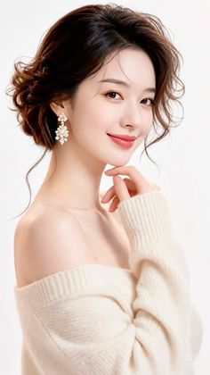 Woman with curly updo and off-shoulder sweater posing against a white background