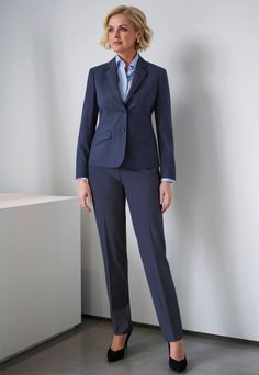 Woman in a navy blue suit and light blue shirt standing indoors