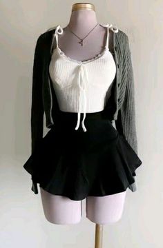 Full body shot of a mannequin wearing a white crop top, black mini skirt, and grey cardigan