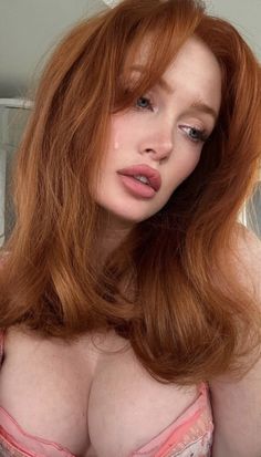 Woman with red hair and a teardrop on her cheek, wearing pink lingerie