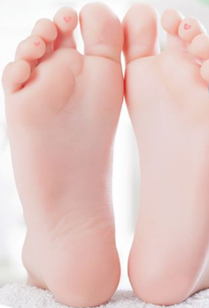 Close up of baby feet with small pink hearts on the toes