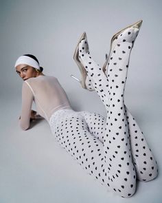 Woman in polka dot leggings and sheer top lying on a white surface