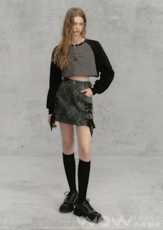 Woman with long hair wearing a crop top and mini skirt with knee-high socks