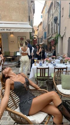 Woman in a polka dot dress reclining in a chair on a cobblestone street