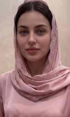 Woman with dark hair and blue eyes wearing a pink hijab with lace trim