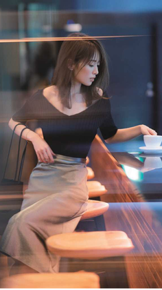 Woman with long hair in a black top and midi skirt at a cafe