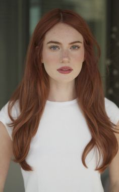 Woman with long red hair and freckles wearing a white t-shirt