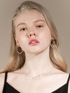 Woman with blonde hair wearing hoop earrings and a layered necklace