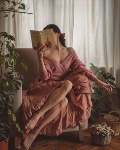 Woman in a pink dress reading a book indoors with soft lighting