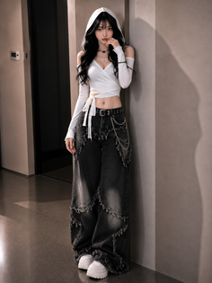 Woman in a white cropped hoodie and wide leg jeans posing indoors
