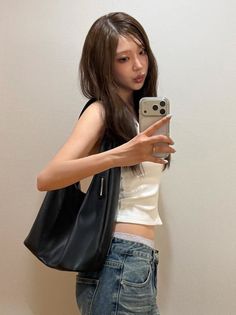 Woman in a white crop top and jeans taking a mirror selfie