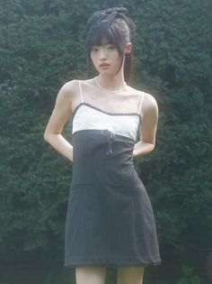 Woman in a black pinstripe dress and hat with a pearl necklace outdoors