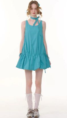 Woman in a blue dress with a matching choker and white socks on a white background