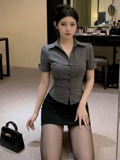 Woman in a gray shirt and black mini skirt kneeling on the floor