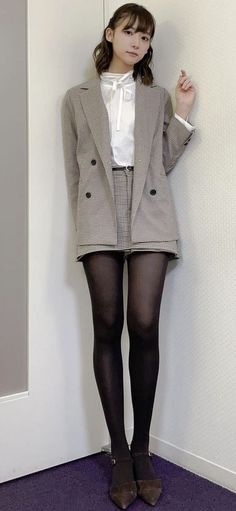 Woman in a plaid blazer and black tights standing indoors