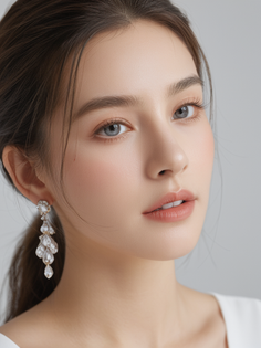 Woman with a ponytail and long crystal earrings looking directly at the viewer