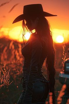 Woman in a cowboy hat and leather outfit silhouetted against a sunset