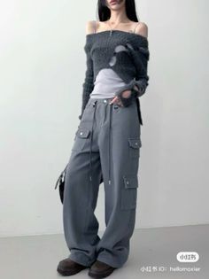 Person in a ripped off-shoulder sweater and cargo pants indoors