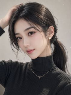 Woman with black hair in a ponytail wearing a black turtleneck and jewelry