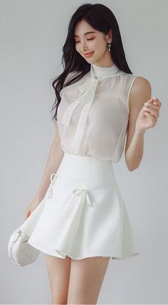 Woman in a white sheer blouse and mini skirt with a white handbag
