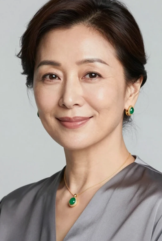 Woman wearing green and gold jewelry with a soft smile