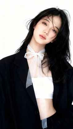 Woman with black hair wearing a white tube top and black blazer with a ribbon