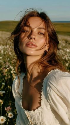 Woman with long hair in a white dress in a flower field at golden hour