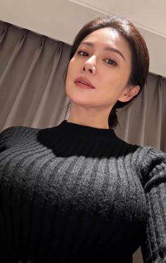 Woman with dark hair wearing a black sweater indoors