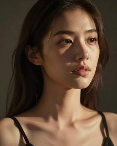 Woman with long hair in a black top, lit by soft, warm light