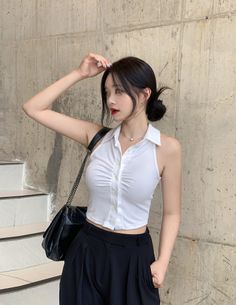 Woman with black hair in a white top and black pants indoors