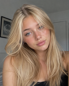 Young woman with long blonde hair and blue eyes in a soft-lit indoor portrait