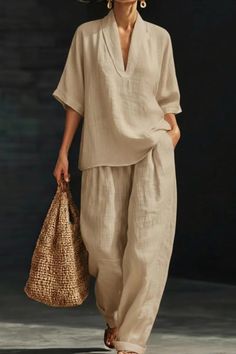 Woman in a linen top and wide leg pants holding a straw bag