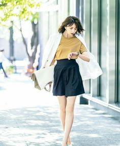 Woman in a white blazer and black shorts walking on a sunny street