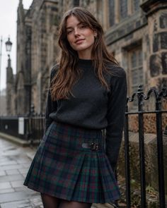 Woman in a dark sweater and plaid skirt on a street with old buildings