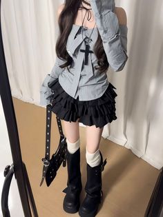 Person in an off-shoulder top and ruffle skirt with platform boots reflected in a mirror