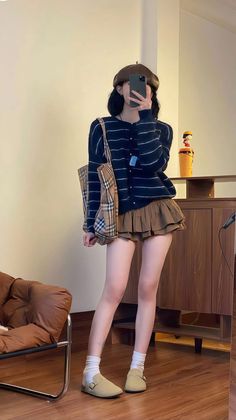 Person in a beret and striped cardigan taking a mirror selfie