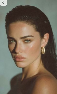 Woman with dark hair and gold earrings in a dramatic portrait with exposed skin