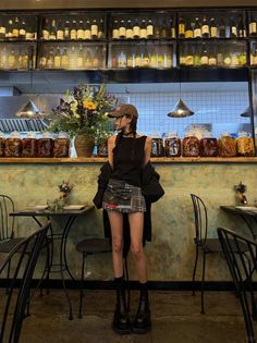 Woman in a plaid skirt and baseball cap standing in a restaurant