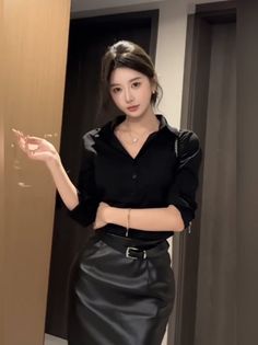 Woman in a black shirt and leather skirt posing indoors