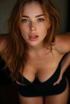 Woman with red hair and freckles in a provocative pose, looking up at the viewer