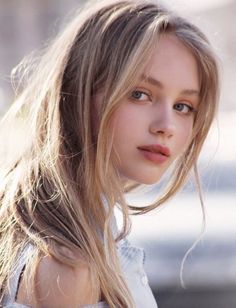 Young woman with long blonde hair and blue eyes in soft lighting