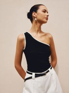 Woman in a black one-shoulder top and white shorts with a black belt