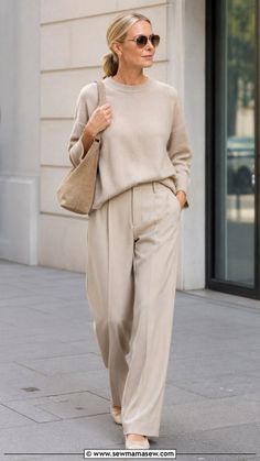 Woman in a beige sweater and wide leg pants walking on a street