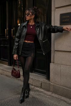 Woman in a leather jacket and mini skirt posing on a city street