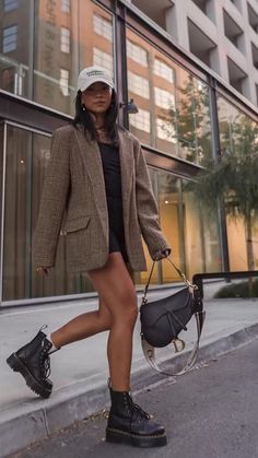 Woman in a plaid blazer and black dress walking on a city street