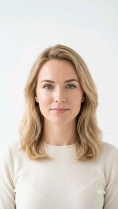 Woman with blonde hair and blue eyes in a portrait shot against a white background