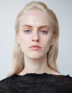 Woman with blonde hair and blue eyes wearing a black top