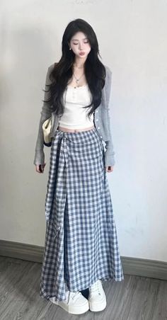 Woman with long black hair wearing a plaid skirt and white top