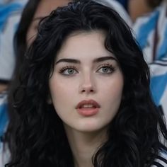 Woman with long black hair and green eyes looking up, indoors