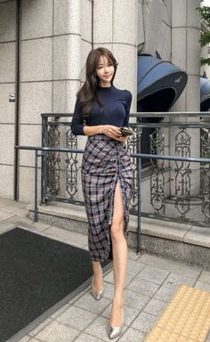 Woman with long hair wearing a plaid skirt with a high slit and silver heels